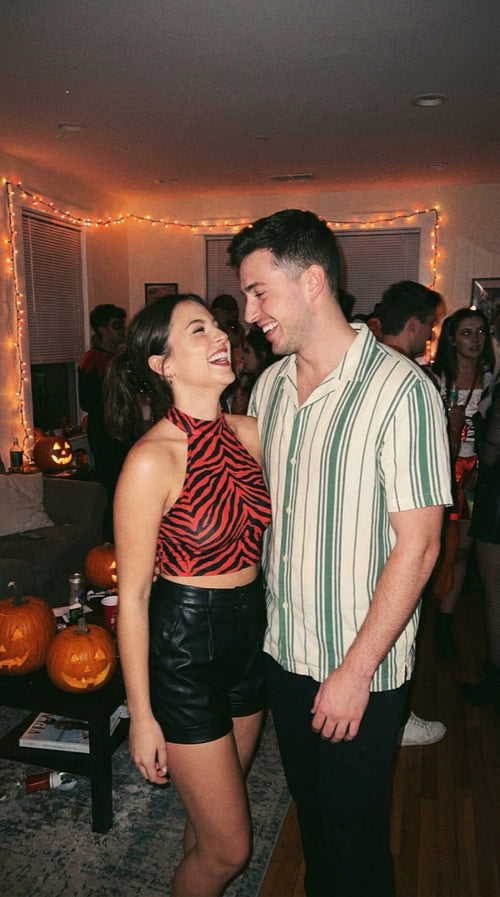 Couples costume: red zebra halter top with black shorts and a green striped camp shirt